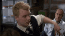 a man in a vest and tie is pointing