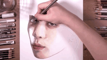 a person is drawing a woman 's face with faber castell pencils in the background