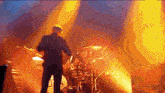 a man playing a guitar on a stage with a drum set