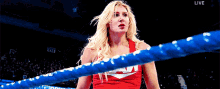 a woman in a red shirt is standing in a boxing ring with the words live on the bottom right