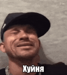 a man wearing a hat is smiling with his eyes closed and making a funny face .