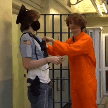 a man in an orange jumpsuit holds hands with a man in a mask
