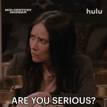 a woman is sitting at a table with glasses of wine and the words are you serious