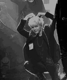 a black and white photo of a man in a black jacket kneeling down .