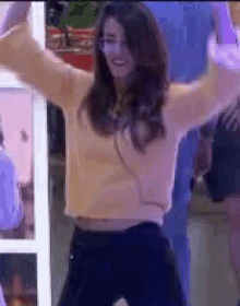 a woman is dancing with her arms in the air while wearing a sweater and black pants .