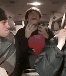 a man is laughing in the back seat of a car with two other people