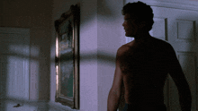 a shirtless man is standing in front of a framed picture