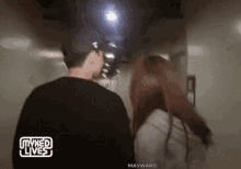 a man and a woman are walking down a hallway with mixed lives written on the bottom right