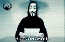 a man in a hooded sweatshirt is holding a piece of paper and the words hugnomous are on the screen behind him