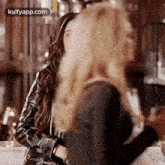 a woman in a leather jacket is sitting at a table in a bar .