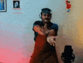a man wearing headphones and a hat is dancing in front of a microphone in a room .