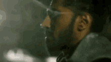 a close up of a man with a beard smoking a cigarette .