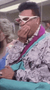 a man wearing sunglasses is covering his mouth