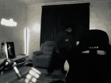 a blurry picture of a man standing in a living room with a chair in the foreground