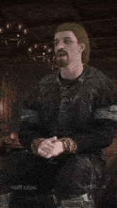 a man with a beard is sitting in front of a sign that says " to an imperial "