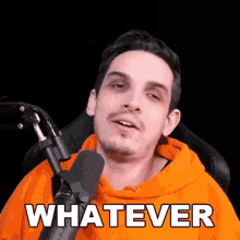 a man in an orange hoodie is sitting in front of a microphone with the word whatever above him