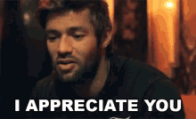 a man with a beard is sitting at a table and says i appreciate you