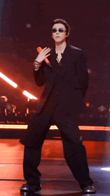 a man in a suit is holding a microphone and dancing on a stage .
