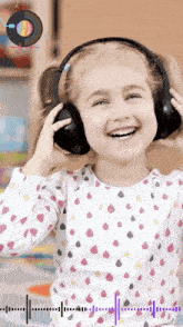 a little girl wearing headphones and smiling with a record in the background