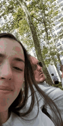 a man and a woman are taking a selfie in front of a tree .
