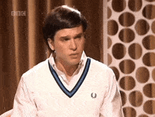 a man wearing a sweater with a bbc logo on the bottom right