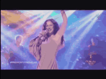 a woman singing into a microphone with the hashtag #premiostvnovelas on the bottom right