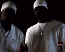 two men are standing next to each other and one has a cross on his necklace