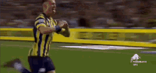 a man in a yellow and blue striped jersey is running on a soccer field .