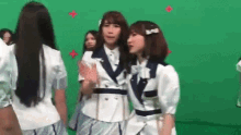 a group of girls are standing in front of a green screen .