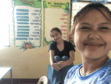 two girls are posing for a picture in front of a bulletin board that says " homework "