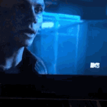a tv screen shows a man in a dark room and a mtv logo