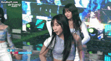 two girls are dancing on a stage in front of a banner that says arirang korea