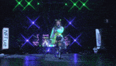 a woman in a futuristic outfit is dancing on a stage with green lights behind her
