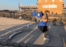 a man in a blue tank top is throwing a discus in front of a crowd