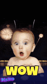 a baby with fireworks in the background and the word wow on the bottom right