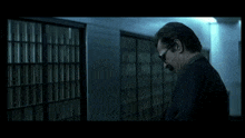 a man with glasses and a mustache is standing in a hallway