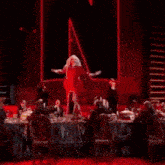 a woman in a red dress is dancing on a stage in front of a black background .