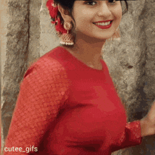 a woman wearing a red dress and earrings is smiling .