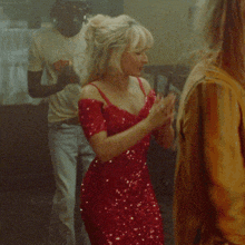 a woman in a red dress is dancing with a man in a coca cola shirt behind her