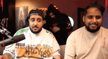 two bearded men are sitting in front of a microphone .