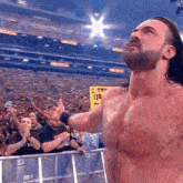 a shirtless wrestler stands in front of a crowd with a yellow sign that says 130