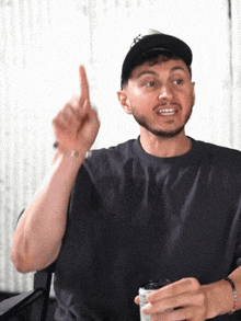 a man with a beard wearing a hat is pointing up