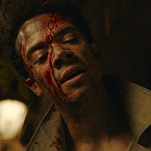 a man with blood on his face and neck is smiling