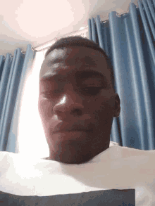 a man laying down with his eyes closed in front of a window