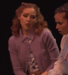 a woman in a purple cardigan is talking to another woman in a blue shirt
