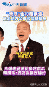 a man in a suit and tie is speaking into a microphone with chinese writing on the bottom