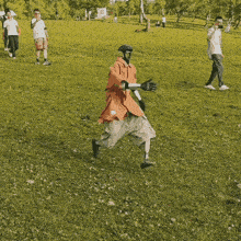 a man wearing a helmet and gloves is walking in a grassy field