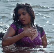 a woman in a purple top is standing in a body of water