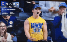 a man wearing a yellow brewers shirt stands in a stadium