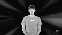 a young man wearing a tribe t-shirt stands in front of a black background